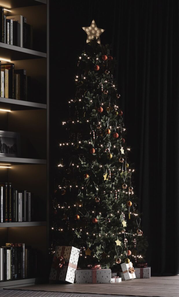 A christmas tree in front of a bookshelf.