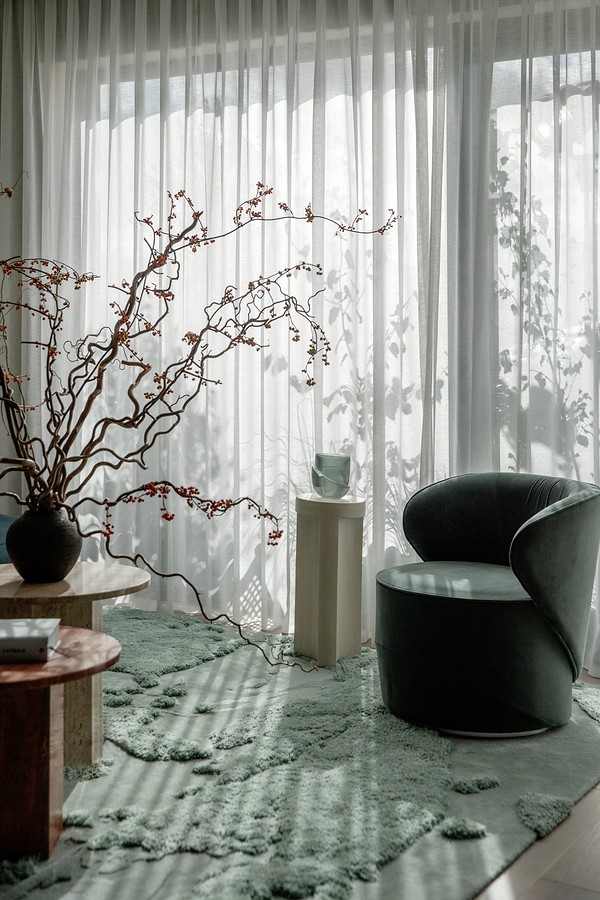 A living room with a green rug and a chair.