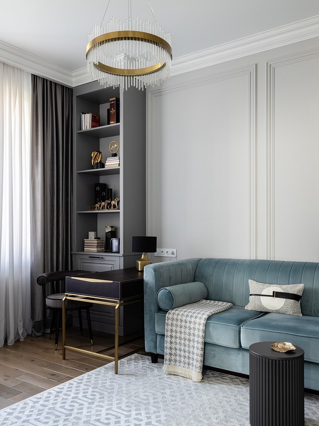 A modern living room with a blue couch and gold accents.