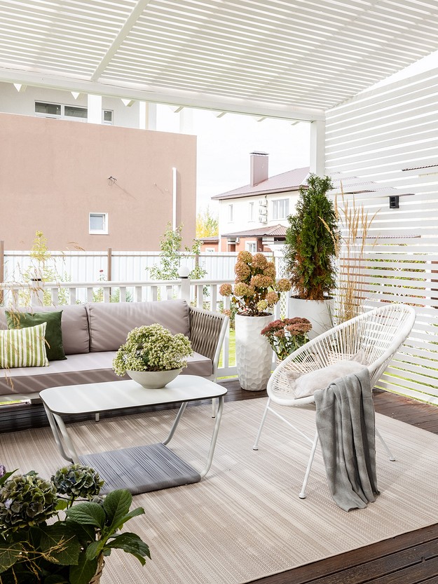 A white covered patio with white furniture and plants.