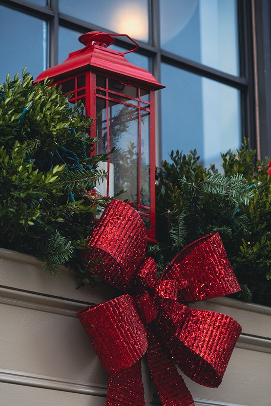 A red lantern with a red bow sits on a window sill.