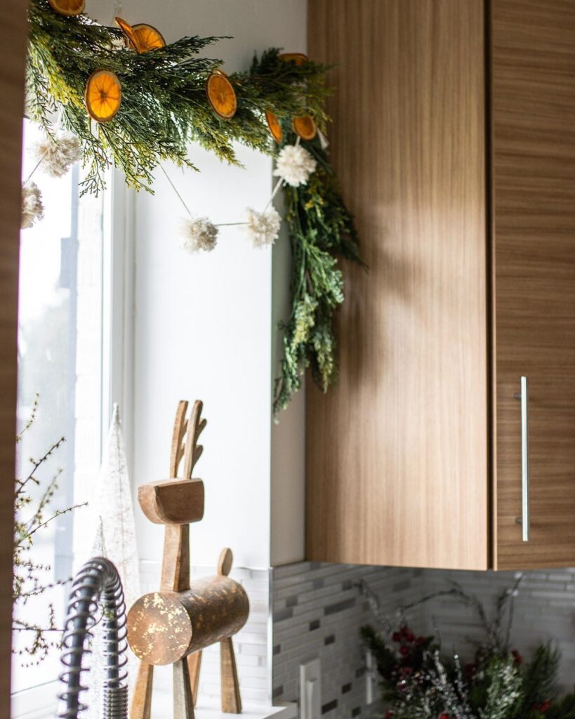 A kitchen with a christmas garland hanging over the sink.