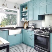 A turquoise kitchen with a black and white floor.