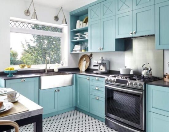 A turquoise kitchen with a black and white floor.